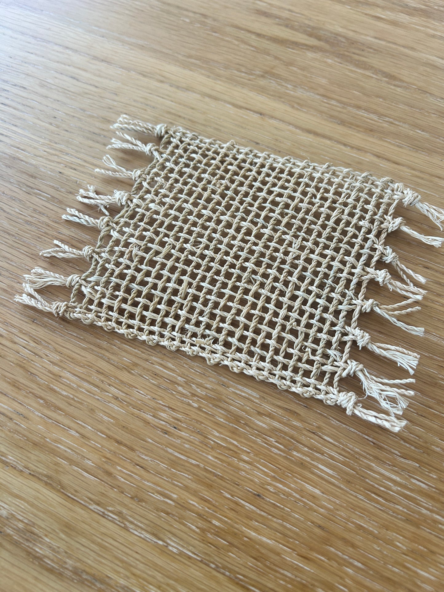 Textured woven raffia coaster on a wooden table