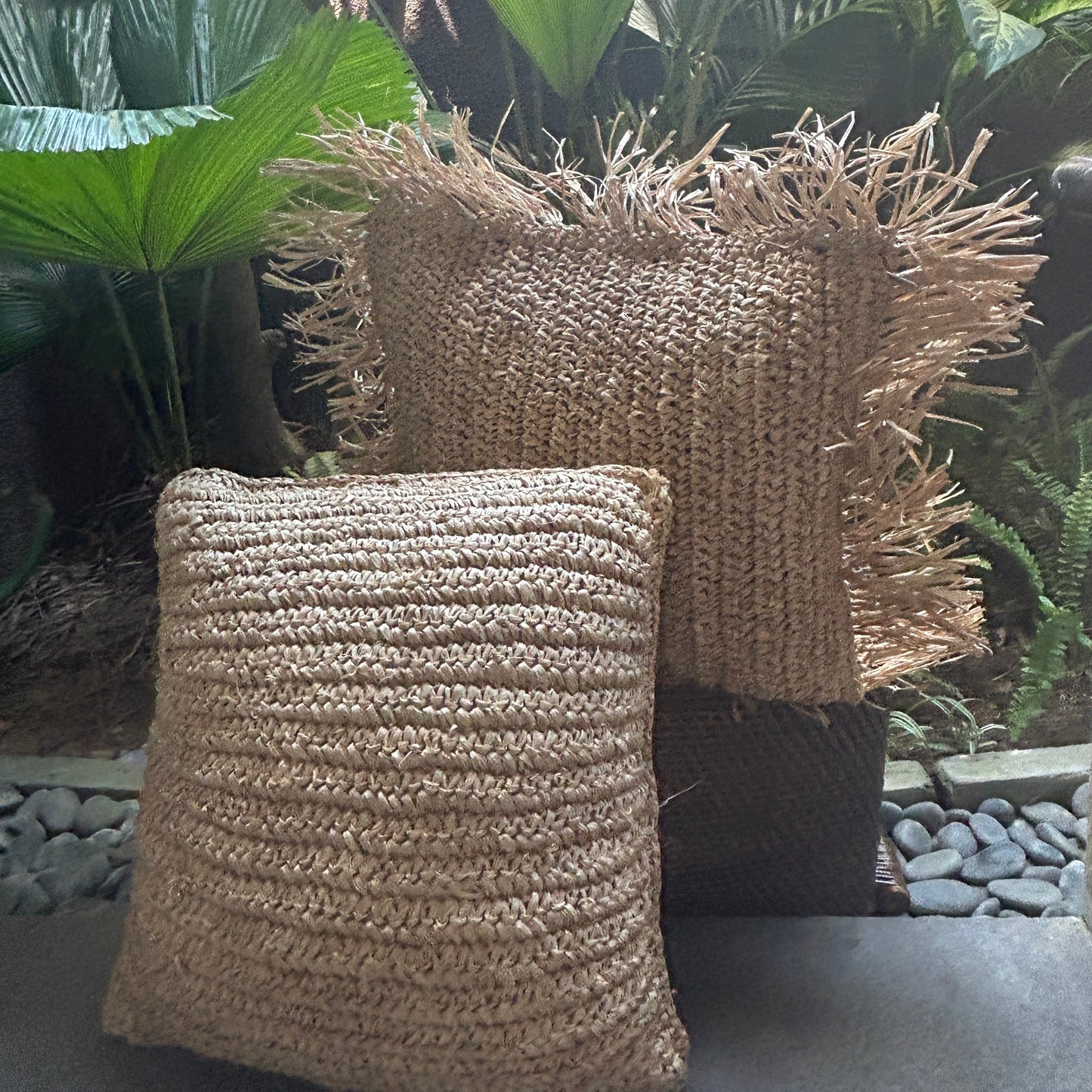 Textured pillows on a decorative surface with green leaves in the background