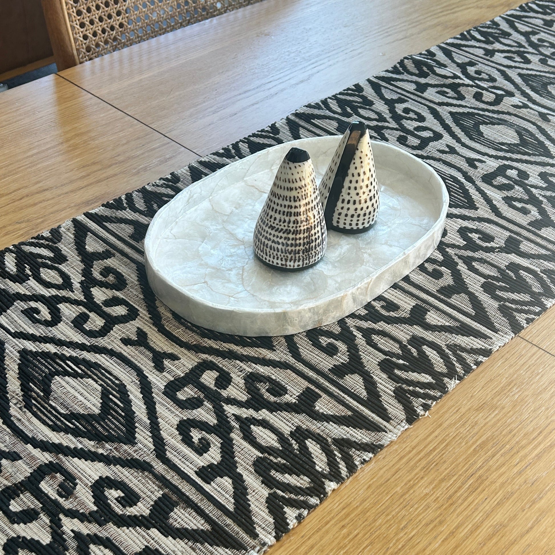 Dining table with a patterned runner and capiz shell tray