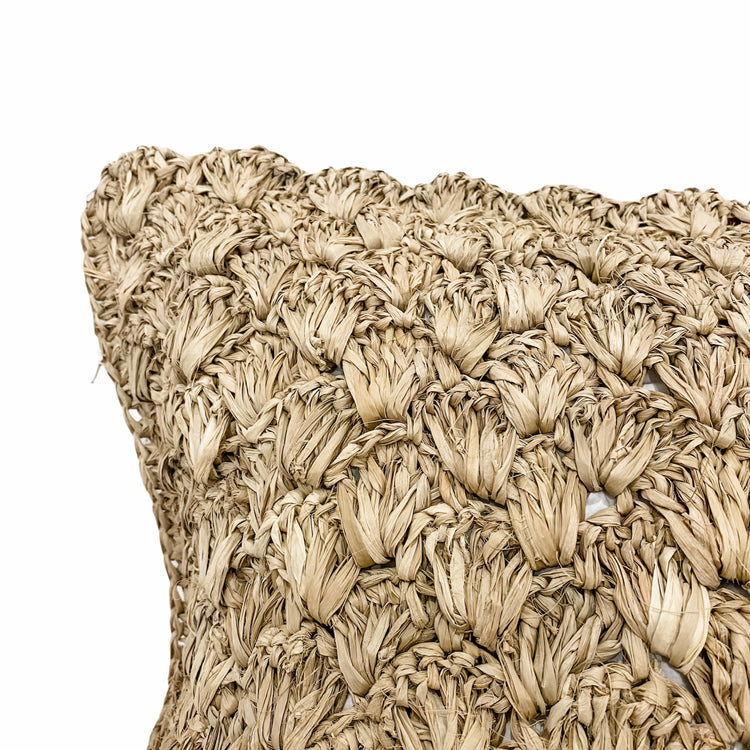 Close-up of a woven throw pillow with a textured raffia - coastal luxe.