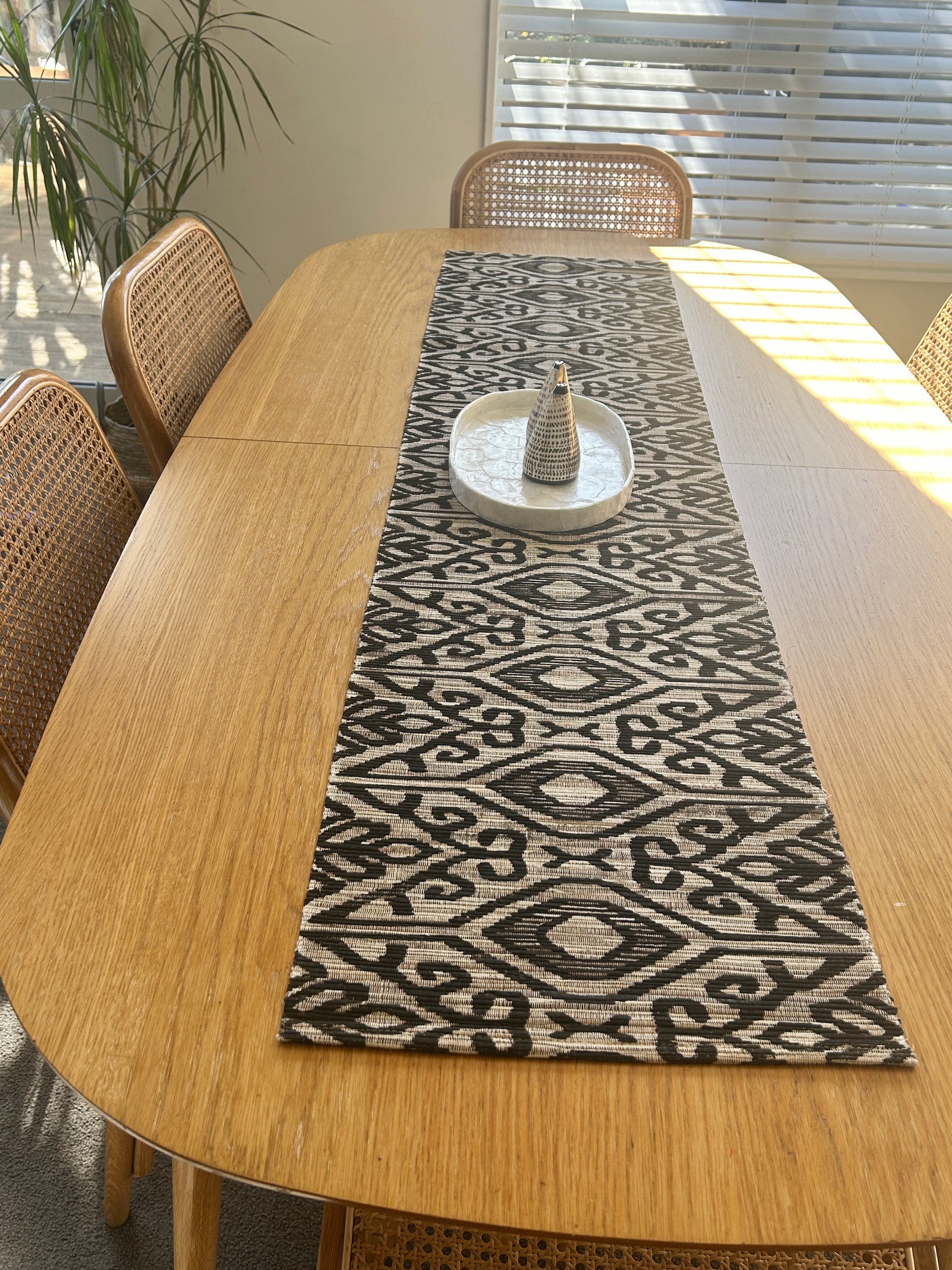 Wooden table with a patterned black and natural ikat table runner