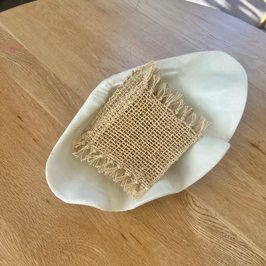 Woven rectangular jute coasters in a white dish on a wooden table - set of 4.