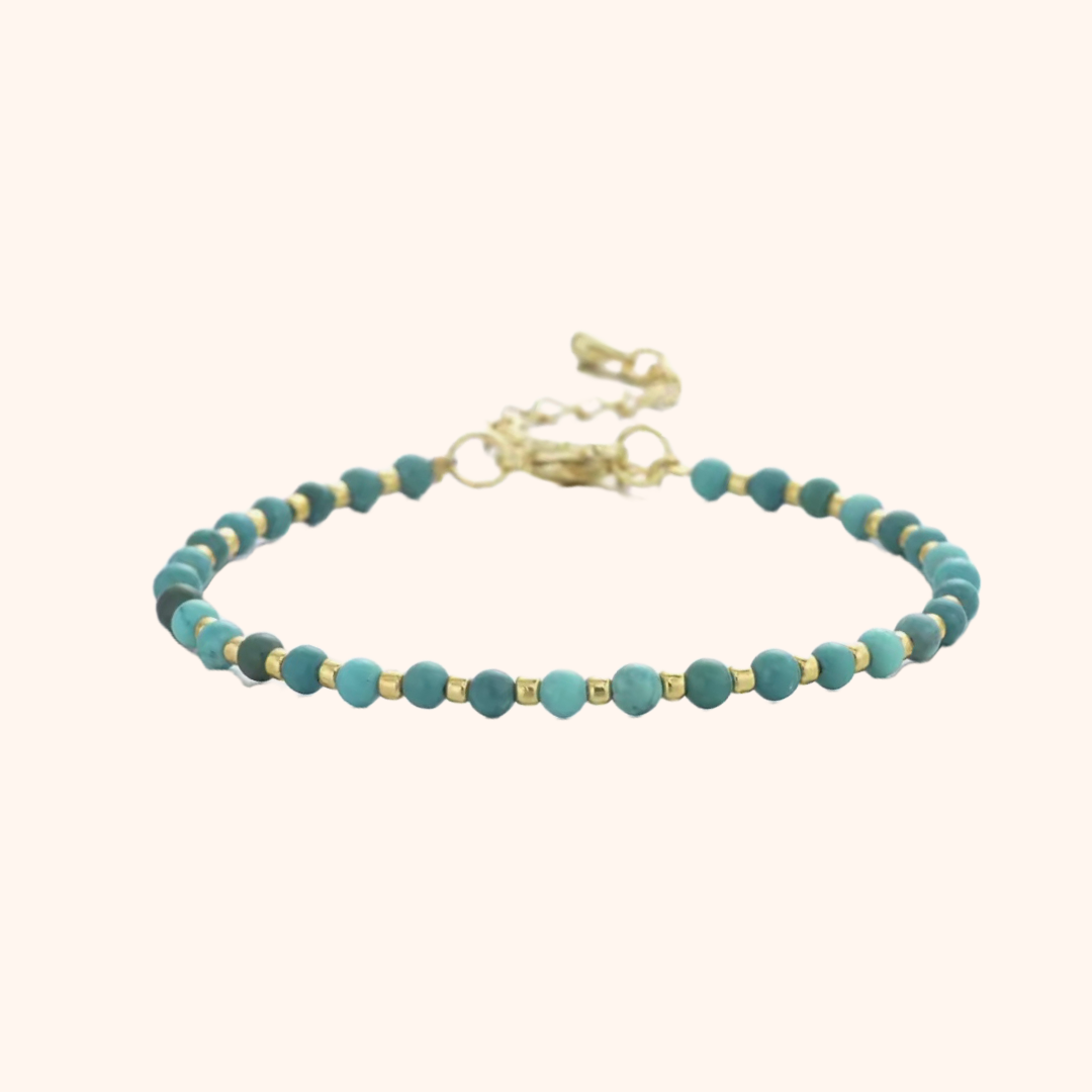 Natural turquoise beaded bracelet with gold plated beads and chain on a white background